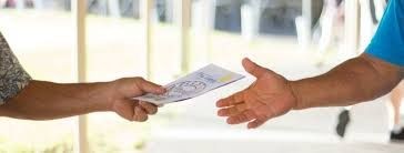 Close-up of two people exchanging a document, with one hand passing it to the other.